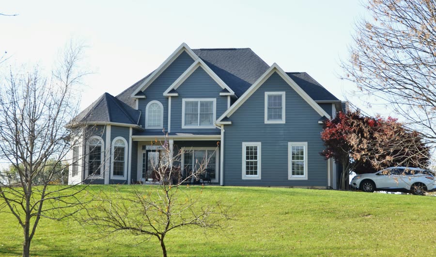A blue two-story house on a green lawn